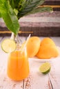 Mango martini and plate of mango and lime. Vase with tropical leaves on left Royalty Free Stock Photo