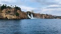 Majestic waterfall cascading from a rocky cliff into the sea in cloudy weather