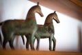 Two small brass horse statues on a shelf