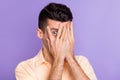 Photo of shy scared anxious young man palm cover face peering wear beige shirt isolated purple color background