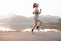 Photo side view Asia young woman runner running on asphalt road at riverside, female in sport cloth jogging at the park Royalty Free Stock Photo