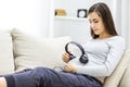 Photo of side view of pregnant woman with headphones on stomach. Royalty Free Stock Photo