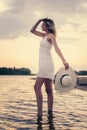 Photo side view of woman with straw hat in her hand. A beautiful young blonde in summer white dress poses against the Royalty Free Stock Photo