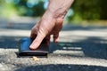 Photo of a sidewalk and the hand of a man who found a black wallet while walking