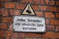 a sign on a brick wall stating Every staying forbade, Jedes Verweilen verboten Royalty Free Stock Photo
