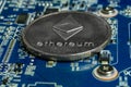 A single Ethereum coin on the blue computer motherboard