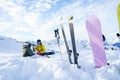 Photo of skis, ski poles, snowboard against background of two sports women with thermos sitting in ski resort in winter Royalty Free Stock Photo