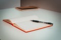 photo from a small angle of a black pen lying on a red open diary on the table Royalty Free Stock Photo