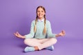 Photo of small peaceful lady sit floor lotus pose wear green sweater pants shoes violet background