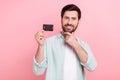 Photo of smart economist young man touch stubble beard demonstrate new credit payment card wear shirt isolated on pink