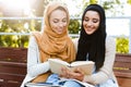 Photo of smart islamic girls wearing headscarfs sitting in green park