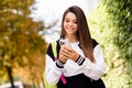 Photo of smart student with straight hairdo dressed stylish jacket rucksack on shoulder read sms on smartphone in sunny