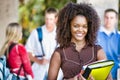 Photo of smiling African American female student on college campus with classmates in background Royalty Free Stock Photo