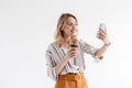 Photo of smiling blonde woman wearing glasses taking selfie photo and holding paper cup Royalty Free Stock Photo