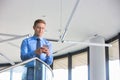 Smiling businessman using smartphone while standing at office Royalty Free Stock Photo