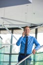 Smiling businessman using smartphone while standing at office Royalty Free Stock Photo