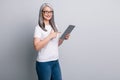 Photo of smiling clever old woman dressed casual outfit eyewear holding pointing modern device isolated grey color