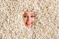 Photo of smiling hungry young woman face showing stick out curious peeking hole covered tasty caramel popcorn