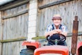 Smiling mature farmer wearing hat while driving tractor