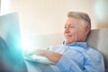 Smiling mature man using laptop while lying on bed at home Royalty Free Stock Photo