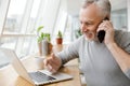 Photo of smiling mature man working with laptop and talking on cellphone Royalty Free Stock Photo