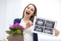 Photo of smiling pregnant woman holding ultrasound result. Royalty Free Stock Photo