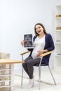 Photo of smiling pregnant woman holding ultrasound result. Royalty Free Stock Photo