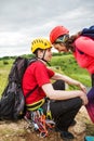 Photo of smiling smiling male tourist in yellow helmet with backpack and carabiners and happy woman on hill Royalty Free Stock Photo