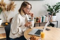 Photo of smiling woman using laptop while having breakfast Royalty Free Stock Photo