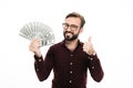 Smiling young man holding money showing thumbs up. Royalty Free Stock Photo