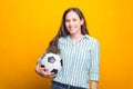 Photo of smiling young woman holding soccer ball over yellow background Royalty Free Stock Photo
