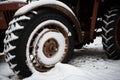 Snow on a rusty wheel of a tractor