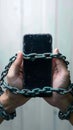 Photo Social media shackles Mobile phone symbolically chained to users hands