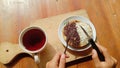 A photo of someone eating a mini martabak and drinking a cup of tea on a wooden table Royalty Free Stock Photo