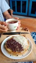 A photo of someone eating a mini martabak and drinking a cup of tea on a wooden table Royalty Free Stock Photo