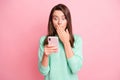 Photo of speechless girl hold smartphone hand close mouth look screen wear teal pullover isolated pink color background