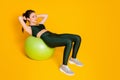 Photo of sportive lady lean big fit ball doing abs sit ups wear sports suit top pants sneakers isolated yellow color Royalty Free Stock Photo