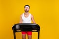 Photo of sporty unsatisfied tired weak guy crying run treadmill empty space isolated on yellow color background