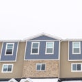 Photo Square Townhouses with snow covered gable roofs against cloudy sky at winter season