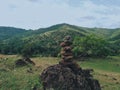 Photo of stack balanced stone at the peak of Maddo Hill, Barru, South Sulawesi, Indonesia with a beautiful landscape at noon.