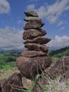 Photo of stack balanced stone at the peak of Maddo Hill, Barru, South Sulawesi, Indonesia with a beautiful landscape at noon. Royalty Free Stock Photo
