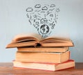 Photo of stack of books over wooden table. top book is open with set of infographics icons. create a better world concept or Royalty Free Stock Photo