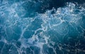 Photo of a stormy sea with foam. Blue surface as background.