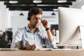 Photo of stressed man 30s wearing office clothes and headset, si Royalty Free Stock Photo