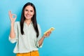 Photo of stunning smart intelligent businesswoman show okay gesture browsing in phone isolated on blue color background