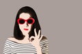 Photo in the style of pop art. Woman in striped dress and sunglasses shows gesture ok.