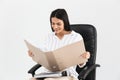 Photo of successful brunette businesswoman 30s smiling and holding bunch of paper folders while sitting in black armchair in Royalty Free Stock Photo