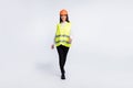Photo of successful worker lady walk wear helmet shirt vest trousers shoes isolated white color background