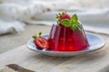 Photo of summer Jelly Dessert with strawberry. Garnished with a sprig of fresh basil on light background. Royalty Free Stock Photo