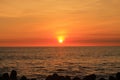 photo of the sun setting in a corner of the beach with the silhouette of a line of breakwaters on the edge